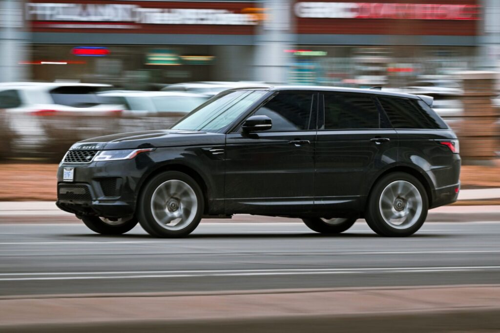 A black SUV speeds through a busy Toronto street, showcasing its elegance and power.