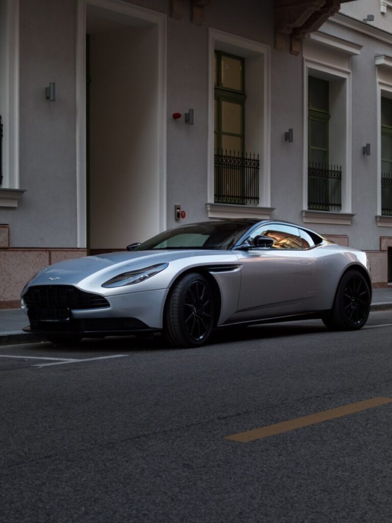 A stylish silver Aston Martin DB11 parked in a modern city street, highlighting luxury and elegance.